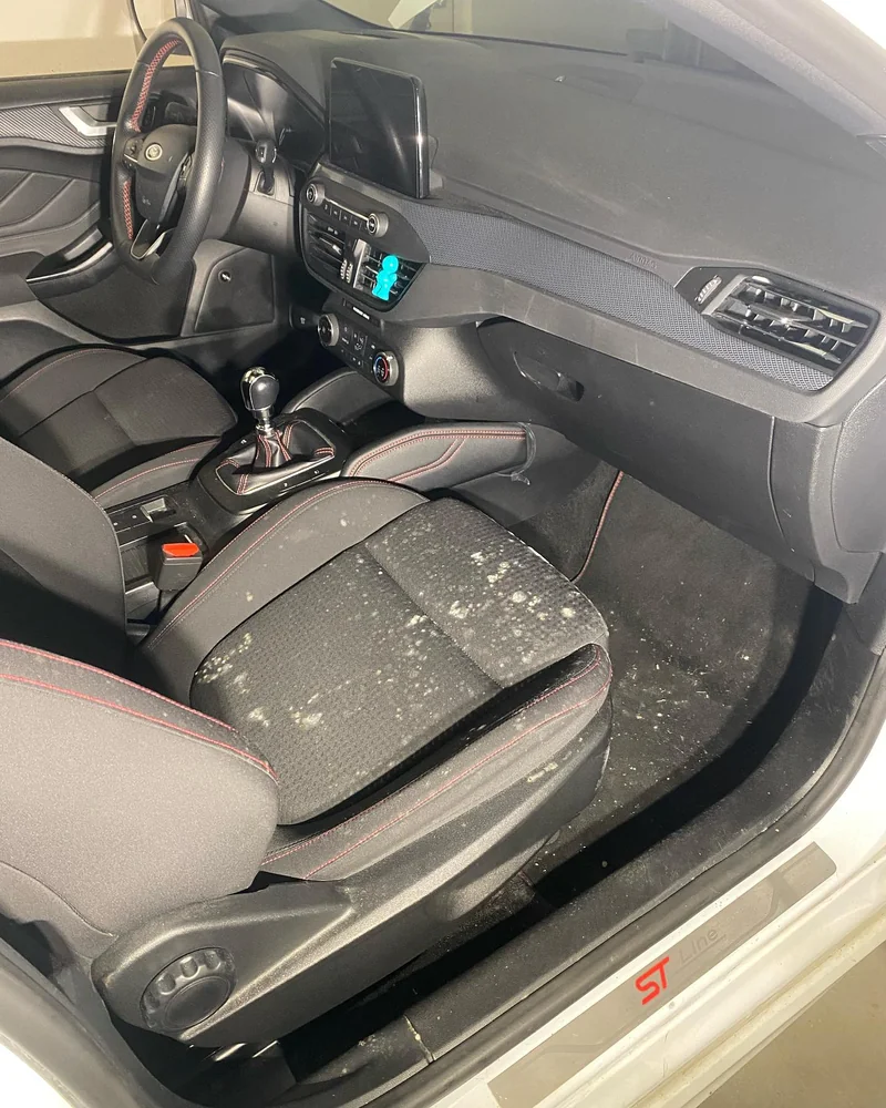 Ford Focus vóór de interieurreiniging met vlekken op de stoel en vervuiling op de vloer